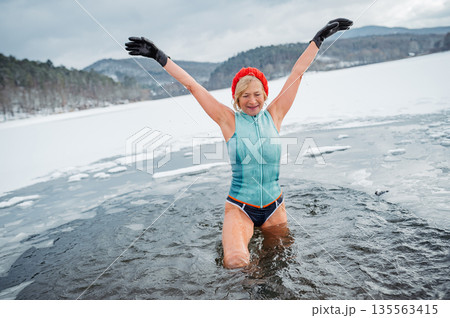 Elderly woman practicing outdoor ice bathing during winter season Elderly woman practicing outdoor ice bathing during winter season 135563415