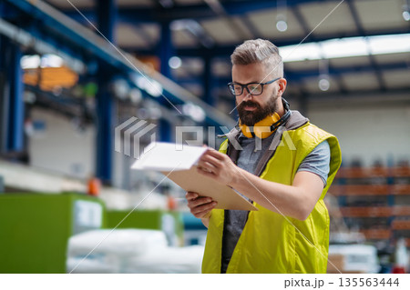 Manager controlling quality of products in factory. Manager controlling quality of products in factory. 135563444