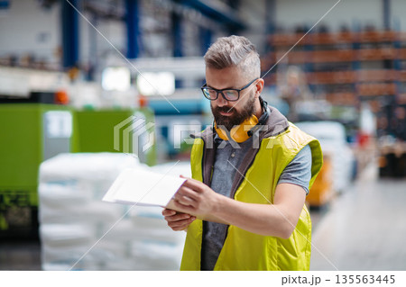 Manager controlling quality of products in factory. Manager controlling quality of products in factory. 135563445