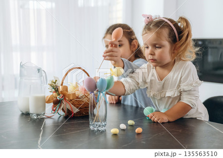 At kitchen, Easter eggs. Two little girls are preparing bakery at home 135563510
