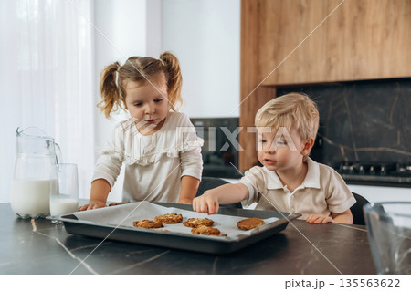 Eating cookies and drinking milk. Kids are preparing bakery at home 135563622