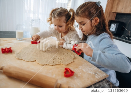 Side view, busy. Two little girls are preparing bakery at home 135563669