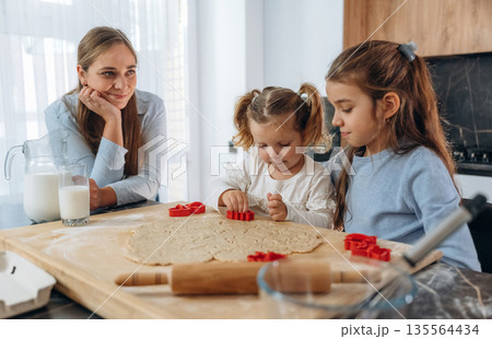 Preparing bakery. Mother with her little daughters at home 135564434