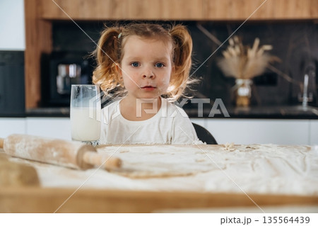 With milk in glass. Little girl is preparing bakery at home With milk in glass. Little girl is preparing bakery at home 135564439
