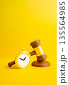 A judge's gavel and stopwatch on a yellow background. Court decisions and deadlines for execution of verdicts. Legal timing concept, enforcement pressure and responsibility for compliance 135564985
