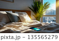 Bright modern bedroom with sunlight streaming through window and smartphone resting on bed, minimalist morning lifestyle concept 135565279
