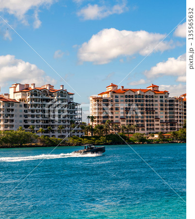 Yacht at Fisher island luxury residential building. Summer vacation. Fisher island building. Luxury motor boat yacht. Yacht go to marina. Boating and yachting. Luxury lifestyle 135565632
