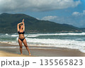 A beautiful girl poses on the beach against the backdrop of sea waves 135565823