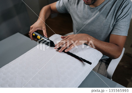 Man performing household chore, steam cleaning and sanitizing pillow, ensuring hygiene, purity and disinfection in bedroom, promoting health and wellness through deep cleaning. 135565993