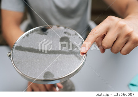 Close-up view of man cleaning dirty table mirror, creating clear streak with finger, illustrating need for hygiene and household chores. Concept of hygiene and cleanliness in domestic environment. 135566007