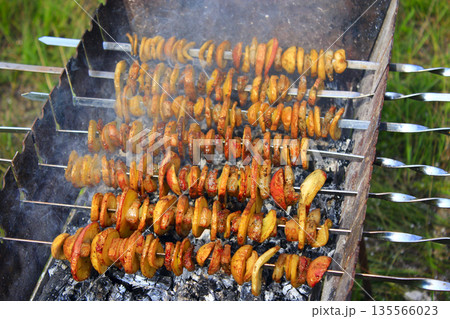 Potato and bakon on skewers cooking on fire. Barbecue lunch 135566023