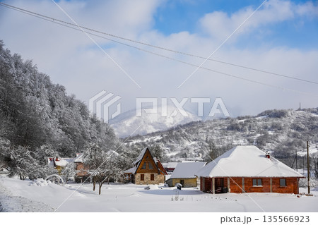 Snowy Cabins in Mountain Forest with Large Snow-Covered Peak Snowy Cabins in Mountain Forest with Large Snow-Covered Peak 135566923