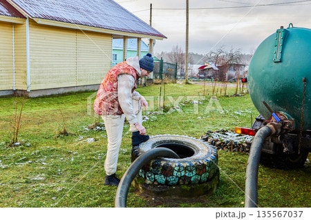 Pumping sewage from septic tank using vacuum truck hose as worker controls suction process and ensures complete removal of liquid waste. 135567037