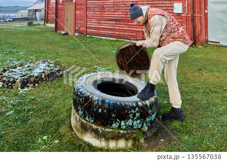 Sanitation worker preparing septic tank access by lifting cover over concrete ring before sewage pumping during routine wastewater management operation. Sanitation worker preparing septic tank access by lifting cover over concrete ring before sewage pumping during routine wastewater management operation. 135567038