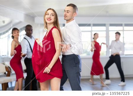 Group of young active people practicing vogue dancing movements while training twist or charleston in dance hall Group of young active people practicing vogue dancing movements while training twist or charleston in dance hall 135567225