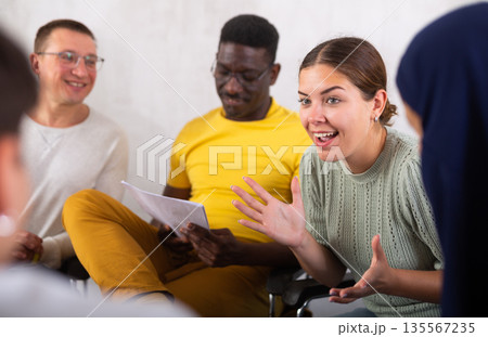 Group of multinational people have discussion while sitting on chairs in circle Group of multinational people have discussion while sitting on chairs in circle 135567235