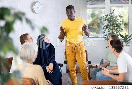Group of multinational people have discussion while sitting on chairs in circle Group of multinational people have discussion while sitting on chairs in circle 135567251
