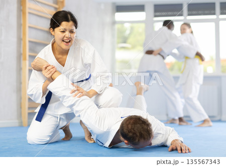 Cosmopolite sportsmen train of performing protection with wring hands during training in aikido Cosmopolite sportsmen train of performing protection with wring hands during training in aikido 135567343