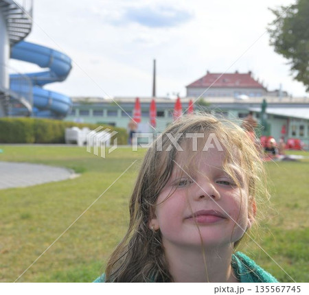 A cute little girl at the swimming pool. A girl wrapped in a towel at the swimming pool. Little happy girl in sunglasses on vacation. Sunny warm summer day, travel concept. The concept of summer A cute little girl at the swimming pool. A girl wrapped in a towel at the swimming pool. Little happy girl in sunglasses on vacation. Sunny warm summer day, travel concept. The concept of summer 135567745