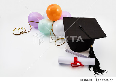 Graduation cap, diploma, and balloons celebrating academic achievement 135568077