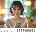 スマートフォンで成功や合格を確認しガッツポーズする若い女性：プレゼン資料やWebデザイン用人物素材 135569951