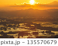 朝日に照らされる水田と山並みの風景 135570679