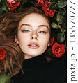 Portrait of beautiful woman amongst red roses backdrop 135570727