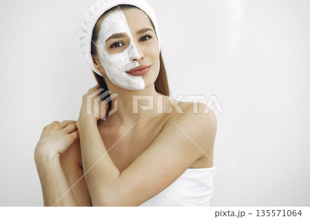 Cosmetology theme. Girl in a white bandage. Woman with mask on face. Cosmetology theme. Girl in a white bandage. Woman with mask on face. 135571064