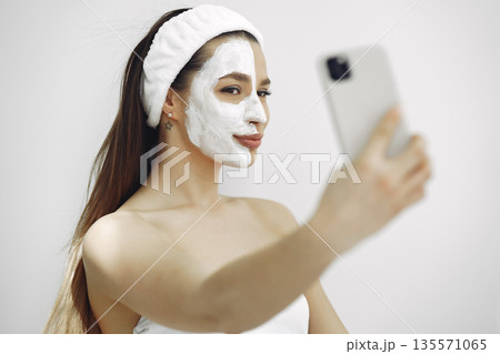 Cosmetology theme. Girl in a white bandage. Woman with mask on face. Cosmetology theme. Girl in a white bandage. Woman with mask on face. 135571065