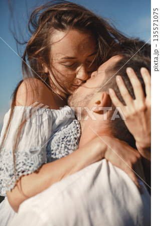 Man and woman in the mountains. Young couple in love at sunset. Woman in a blue dress. Peopel standing on a sky background. Man and woman in the mountains. Young couple in love at sunset. Woman in a blue dress. Peopel standing on a sky background. 135571075