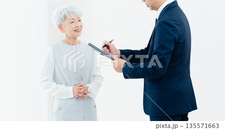 営業マンの説明を聞くシニア女性 営業マンの説明を聞くシニア女性 135571663