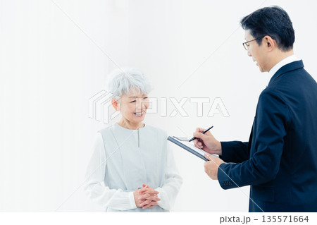営業マンの説明を聞くシニア女性 135571664