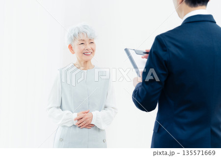 営業マンの説明を聞くシニア女性 135571669