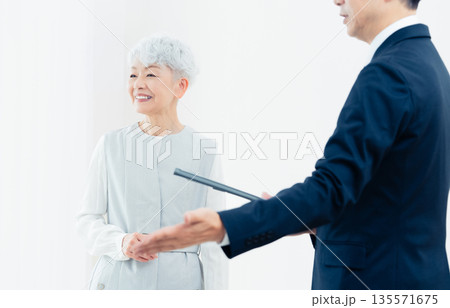 営業マンの説明を聞くシニア女性 135571675