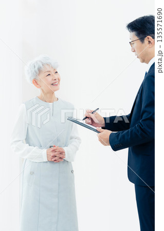 営業マンの説明を聞くシニア女性 135571690