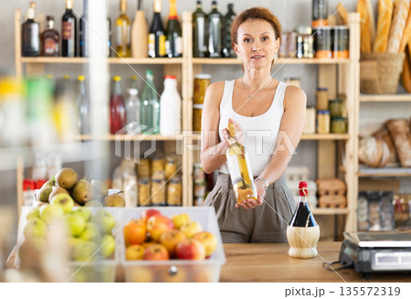 Female salesperson offers to buy bottle of wine in liquor department of grocery supermarket 135572319