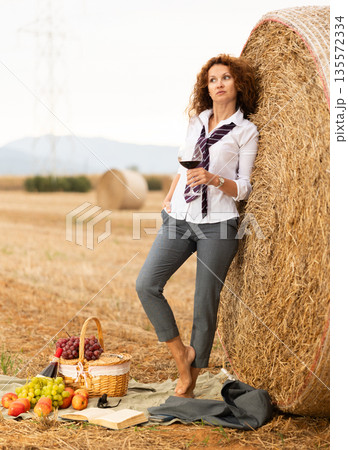 Relaxed woman in business attire enjoying wine during country retreat Relaxed woman in business attire enjoying wine during country retreat 135572334