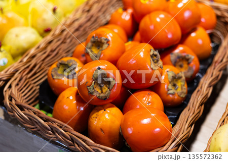 High quality imported eco persimmon grouped stored in window in wicker basket. High quality imported eco persimmon grouped stored in window in wicker basket. 135572362