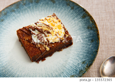 Restaurant serves dessert - ceramic plate accommodates small piece of brownie sponge cake Restaurant serves dessert - ceramic plate accommodates small piece of brownie sponge cake 135572365