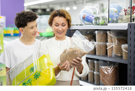 Family mom and son in animal goods store examines packaging of dry food for turtles Family mom and son in animal goods store examines packaging of dry food for turtles 135572418