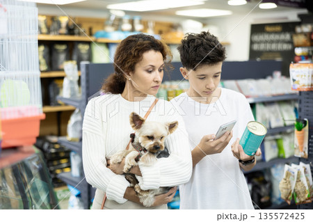 Family with Yorkshire terrier puppy is scaning QR code on dog food tin can at pet shop 135572425