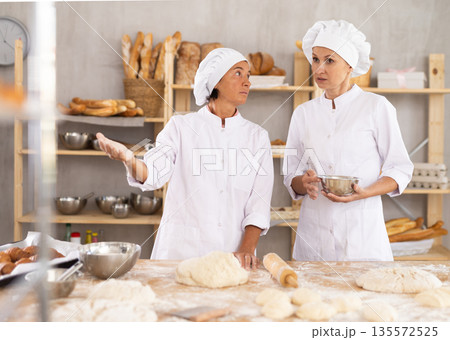 Two women bakers having discussion about work Two women bakers having discussion about work 135572525