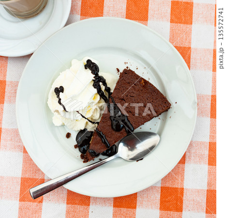 Restaurant serves dessert - ceramic plate accommodates small piece of brownie sponge cake 135572741