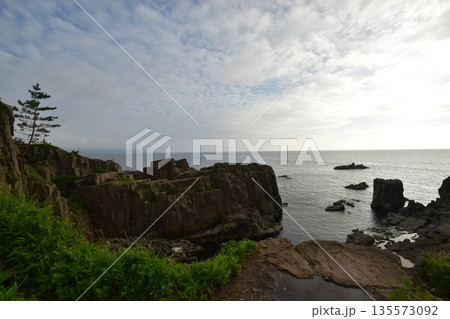 福井県の景勝地である東尋坊の柱状節理の岩肌と日本海が織りなすダイナミックな自然風景 135573092