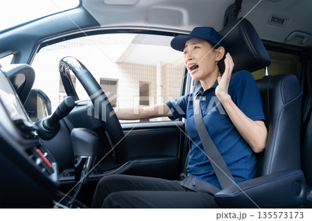 車で荷物を配達するミドルの女性配達員 車で荷物を配達するミドルの女性配達員 135573173