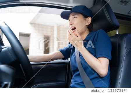 車で荷物を配達するミドルの女性配達員 車で荷物を配達するミドルの女性配達員 135573174