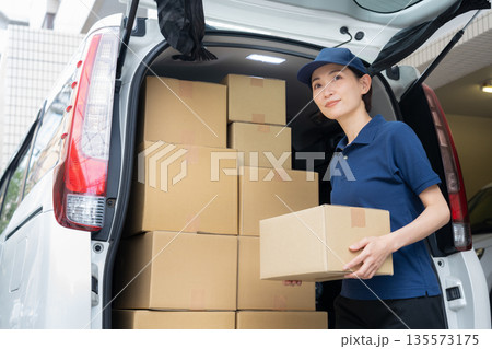 車で荷物を配達するミドルの女性配達員 車で荷物を配達するミドルの女性配達員 135573175