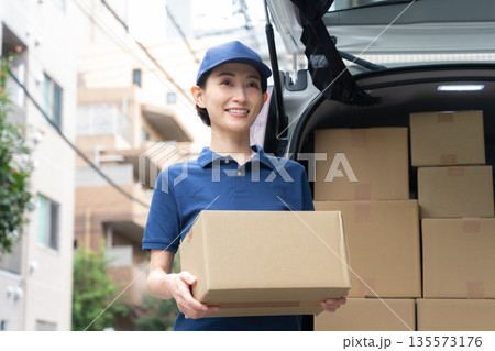 車で荷物を配達するミドルの女性配達員 135573176