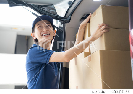 車で荷物を配達するミドルの女性配達員 車で荷物を配達するミドルの女性配達員 135573178