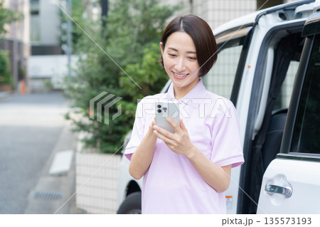 車で訪問介護をするミドルの女性介護士 車で訪問介護をするミドルの女性介護士 135573193